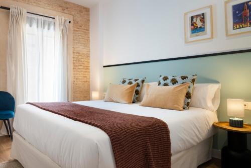 1 dormitorio con 1 cama grande con sábanas y almohadas blancas en Magno Apartments Feria 132 en Sevilla