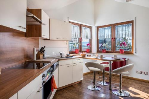 uma cozinha com armários brancos e uma mesa e cadeiras em Dreiländereck em Hartheim