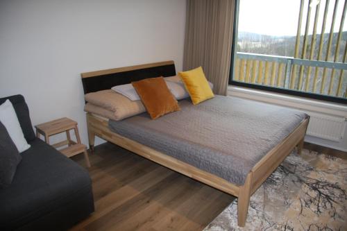 a bed with pillows on it in a room with a window at Apartmán na Zadově in Stachy