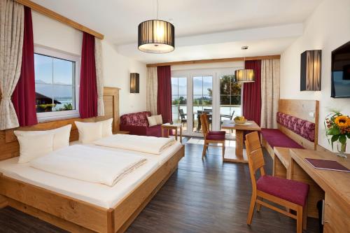 リーデンにあるランドホテル シュヴァルツェンバッハ ウェルネス＆スパのベッドとダイニングルームが備わるホテルルームです。