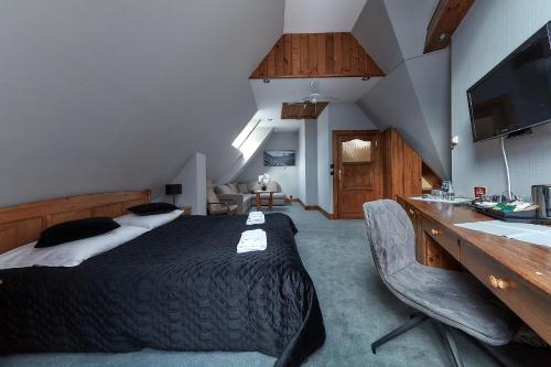 a bedroom with a bed and a desk and a television at Hotel Skalny in Zakopane