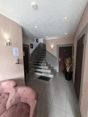 a room with a staircase with a pink chair and stairs at Hotel Eiserner Anton in Bielefeld