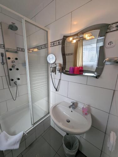 a bathroom with a sink and a shower and a mirror at Hotel Eiserner Anton in Bielefeld