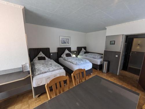 a room with two beds and a table and chairs at Hotel Eiserner Anton in Bielefeld