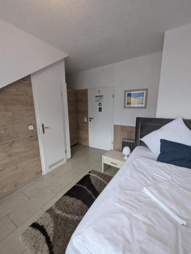 a bedroom with a large white bed and a door at Hotel Eiserner Anton in Bielefeld