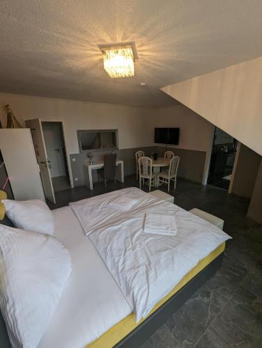a large white bed in a room with a table at Hotel Eiserner Anton in Bielefeld
