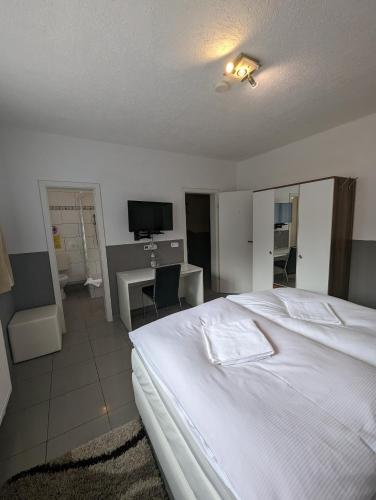 a bedroom with a large white bed and a desk at Hotel Eiserner Anton in Bielefeld