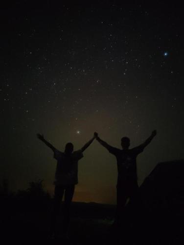 a couple holding their hands up in the night sky at Mirador Valle de la Tatacoa in Villavieja