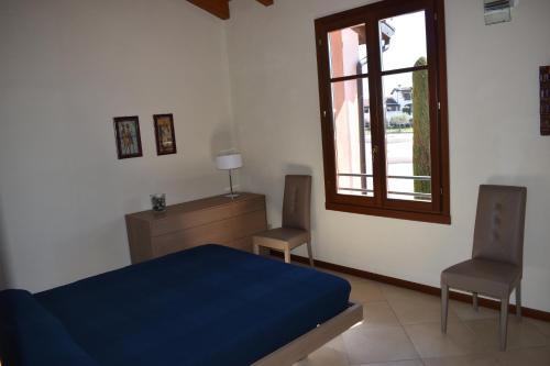 a bedroom with a blue bed and two chairs at Esclusivo trilocale con piscina al Garda Resort Village in Peschiera del Garda