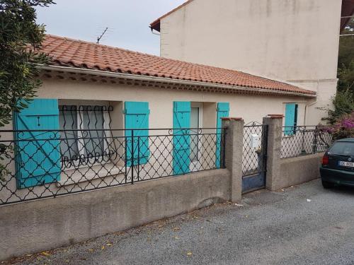 a fence in front of a house with blue doors at La Casita du Dramont 83530 in Saint-Raphaël
