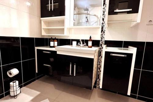 A large, comfortable flat in the best area of Ankara, Turkey في أنقرة: مطبخ مع دواليب سوداء وبيضاء ومغسلة