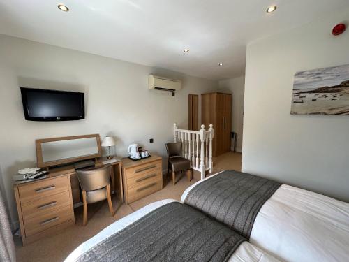 a bedroom with a bed and a desk with a television at Le Friquet Hotel in Castel
