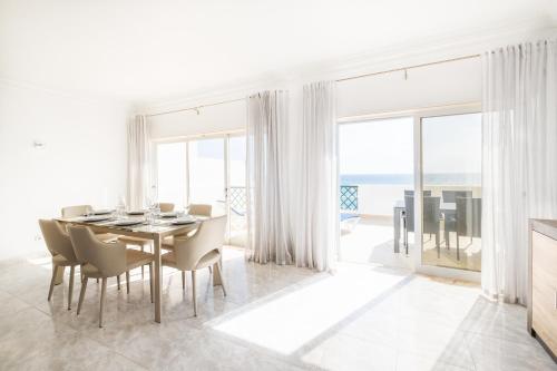 a white dining room with a table and chairs at Frente ao Mar - 3 quartos - wi-fi - AQ in Armação de Pêra