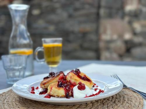 a plate of pancakes with berries and a glass of orange juice at Capra Hotel Kazbegi in Kazbegi