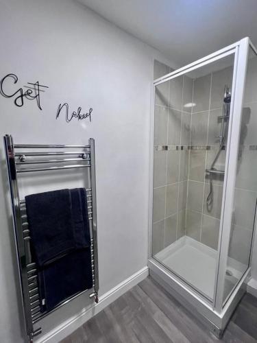 a bathroom with a shower and a blue towel at Prince Arthur Apartment in Walton on the Hill