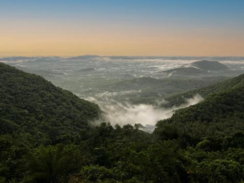 a view of a valley filled with trees and clouds at Vayalada Valley View Resort in Bālūssheri