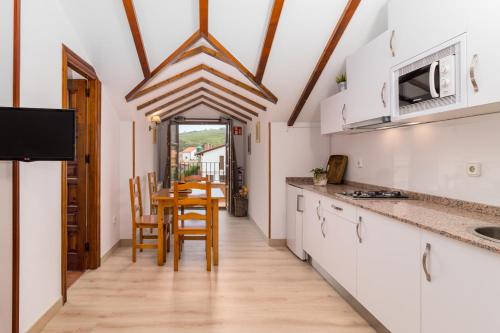 a kitchen with white cabinets and a table with chairs at Apartamentos & Bungalows Ubiarco El Acebo by Alterhome in Ubiarco