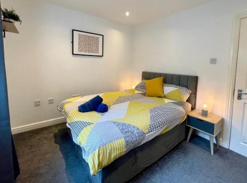 een slaapkamer met een bed met gele en blauwe kussens bij 6 Person Apartment in City Centre in Cardiff