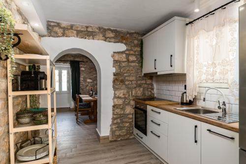 a kitchen with white cabinets and a stone wall at The Greystone House by Konnect, Views to the Sea in Nisakion