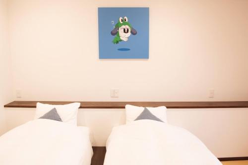 a bedroom with two beds and a picture on the wall at Doggy's Izujogasaki in Ito