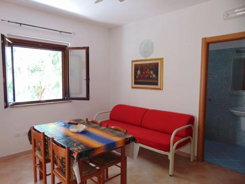 sala de estar con sofá rojo y mesa en Appartamento in Villa con giardino a 200m dal mare, en Vieste