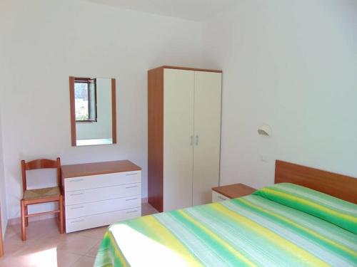 1 dormitorio con cama, tocador y espejo en Appartamento in Villa con giardino a 200m dal mare, en Vieste