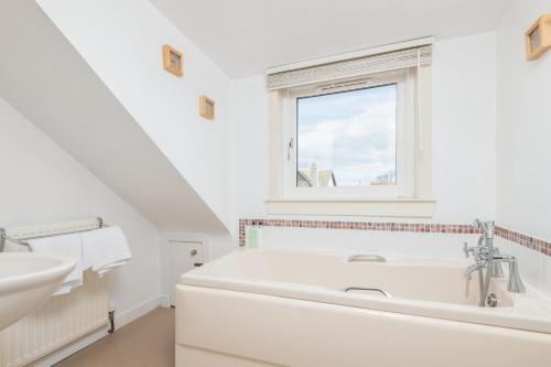 a white bathroom with a sink and a bath tub at The Cooperage - 2 Bedroom, 2 Bathroom with Garden in Crail
