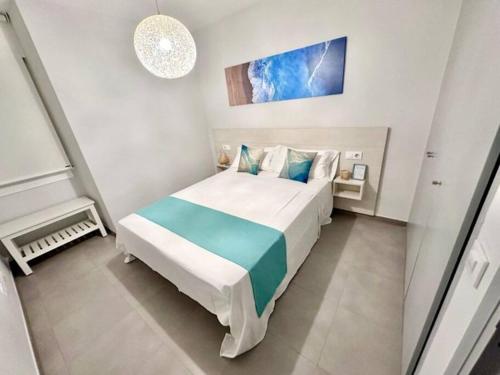 Roses Apartments - Marivent (2rooms) Vistas frontales al mar في روساس: غرفة نوم بسرير أبيض كبير مع وسائد زرقاء