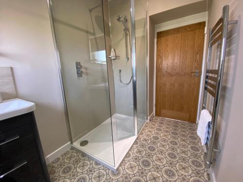La salle de bains est pourvue d'une douche avec une porte en verre. dans l'établissement Croft@42, à Vatsker
