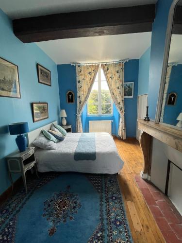 Les Loges-sur-Brécey的住宿－Bed&Breakfast au Château des Boulais，一间卧室设有蓝色的墙壁和一张带窗户的床