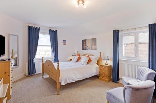 een slaapkamer met een bed met blauwe gordijnen en een televisie bij White Rose Guest House in Filey