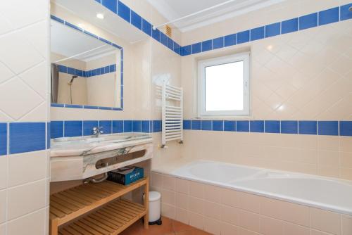 uma casa de banho com uma banheira, um lavatório e um espelho. em Quinta do Morgado By ALGARTUR em Tavira
