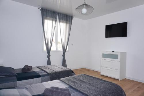 a bedroom with two beds and a flat screen tv at Maison proche de la Plage, Classée 3 étoiles - Le Crotoy in Le Crotoy