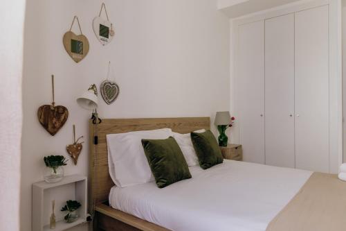 a bedroom with a bed with white sheets and green pillows at Casa Feijão no Centro de Setúbal in Setúbal