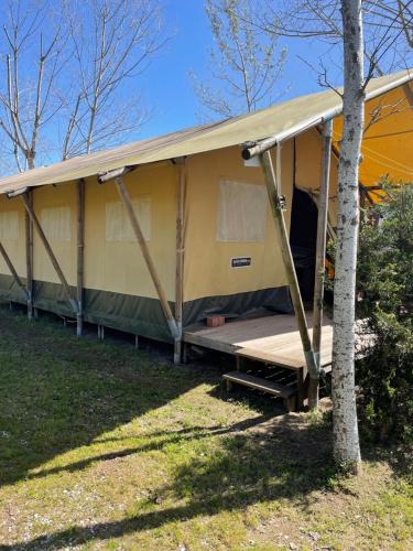 a large yellow house with a porch at Glamping tent with bathroom - Tuscany next to sea! in Viareggio