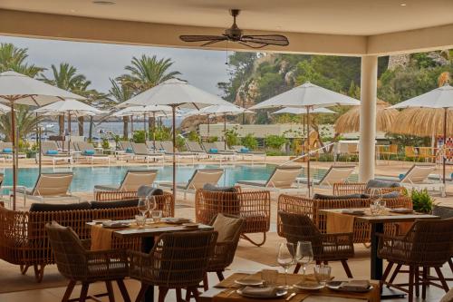 a restaurant with tables and chairs and a pool at Siau Ibiza Hotel in Puerto de San Miguel