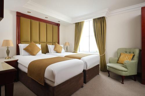 a hotel room with two beds and a chair at The Prime London Hotel in London