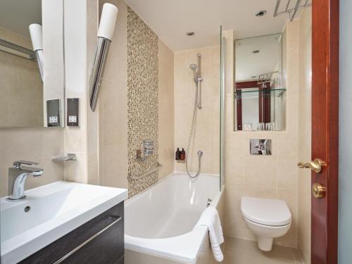 uma casa de banho com uma banheira, um WC e um lavatório. em The Prime London Hotel em Londres
