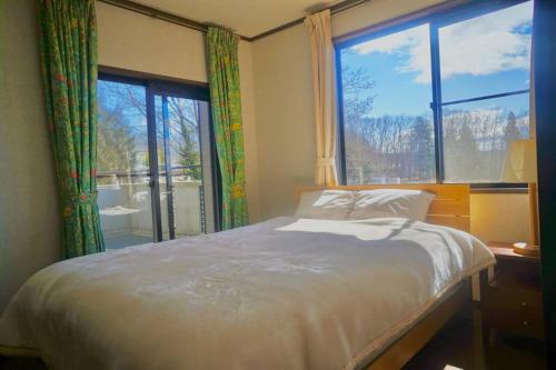 um quarto com uma cama e uma grande janela em Foresta Karuizawa 3 em Miyota