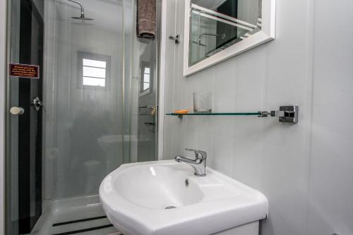 uma casa de banho branca com um lavatório e um chuveiro em SleepOver Matoks em Matoks