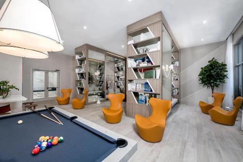 a living room with a pool table and orange chairs at 3 Story Luxury Apt Las Olas FTL in Fort Lauderdale