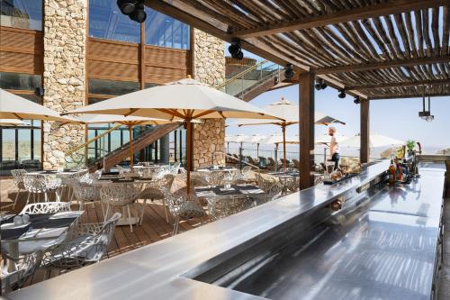 a bar with tables and chairs and umbrellas at Beresheet by Isrotel Exclusive in Mitzpe Ramon