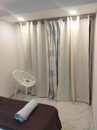 a bedroom with white curtains and a bed and a chair at Seapoint(Seascape) in Dapoli