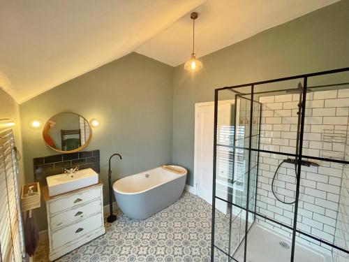 a bathroom with a tub and a sink and a mirror at Ty Capel Vestry in Conwy