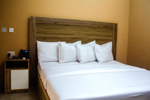 a bedroom with a large white bed with a wooden headboard at Hotel Capitol in Ikeja