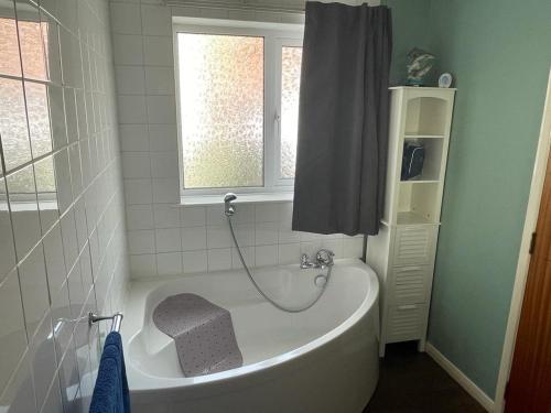 a white bath tub in a bathroom with a window at 2 Bedroom Ground Floor Holiday Apartment Skegness in Skegness