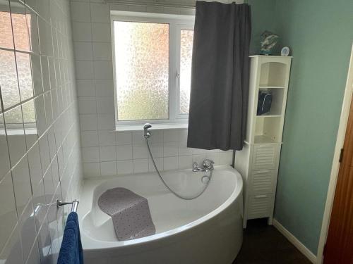 a white bath tub in a bathroom with a window at 2 Bedroom Ground Floor Holiday Apartment Skegness in Lincolnshire