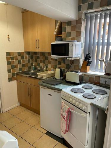 a kitchen with a stove and a microwave at 2 Bedroom Ground Floor Holiday Apartment Skegness in Skegness