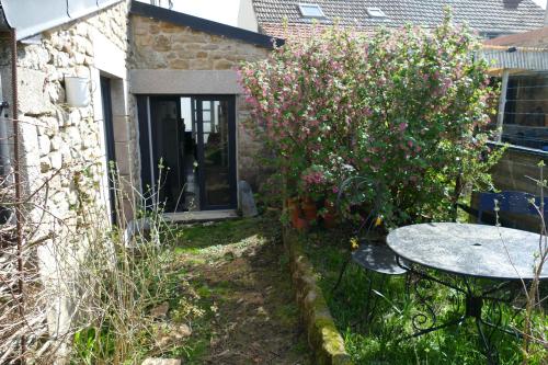 a garden with a table and a bush with pink flowers at Au coeur des landes in Carneville