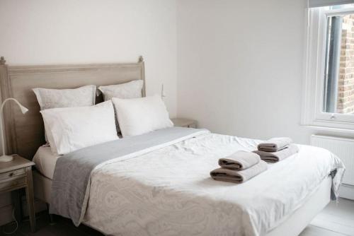 a white bedroom with a bed with towels on it at 3 Bedroom House in Kew Gardens in Richmond